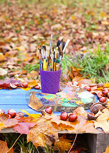 秋季公园的画家在工作场所使用塑料容器中的木质调色板和油漆刷子图片