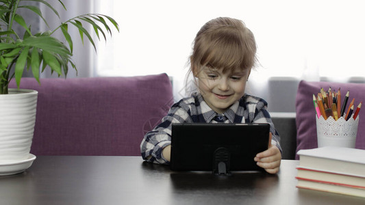 保障服务专注于可爱的孩子听音频课使用数字平板电脑在餐桌上学习背景