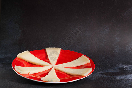 深底红陶瓷板上六片典型的西班牙芒切戈奶酪图片