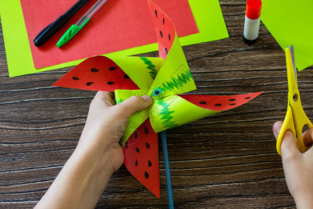 折纸指导步骤10纸风车有趣的玩具西瓜风车在木桌上旋转儿童艺术项目针线活背景图片