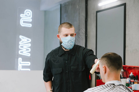一位戴着医用口罩的专业男理发师用剪刀断隔离区的客户理发店在冠状检图片