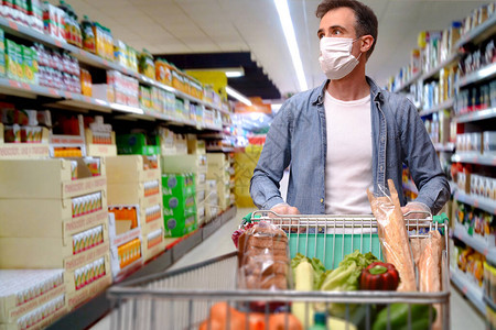 戴面罩和手套的男子在超市里推着一辆图片