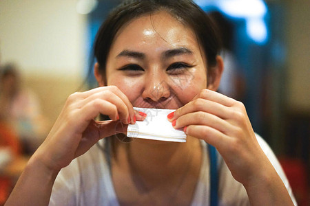 年轻快乐微笑的亚洲女孩在餐厅吃完食物后擦嘴背景图片