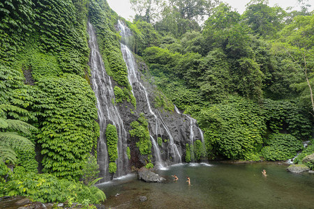 热带雨林中带有岩石和绿宝石蓝色池塘的秘密丛林瀑布级联图片