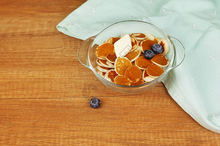 带黄油和蓝莓的迷你煎饼放在木制桌板上的盘子上图片