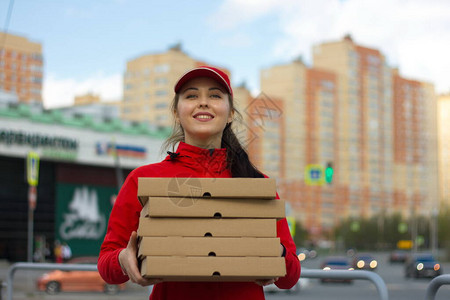 在大城市送披萨送餐的女孩拿着五盒披萨她把箱子举到前面图片