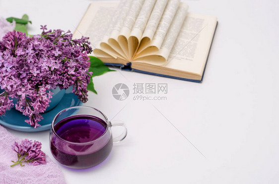 一杯芬芳的紫色Clitoria茶和一束蓝色杯子里的丁香花图片