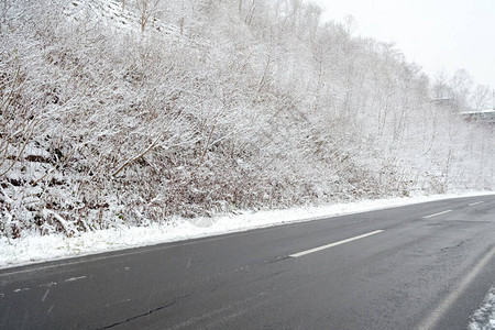 在雪背景的冬天山的柏油路图片