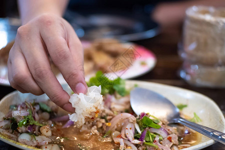 香辣鸡米花特写手指吃白盘中的糯米香辣猪肉沙拉背景
