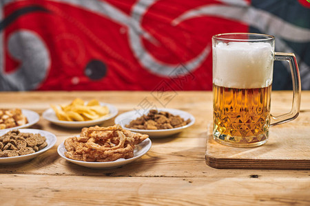 桌上有一杯啤酒和不同的小吃庆祝国际啤酒日或十月节辛勤工作一天或图片