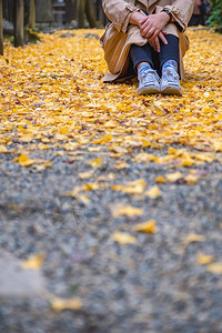 一名妇女独自坐在街上在秋天带着黄色的图片