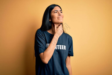 年轻漂亮的西班牙裔女穿着志愿者T恤作为社会慈善道德感人的脖子痛喉咙痛流感背景图片
