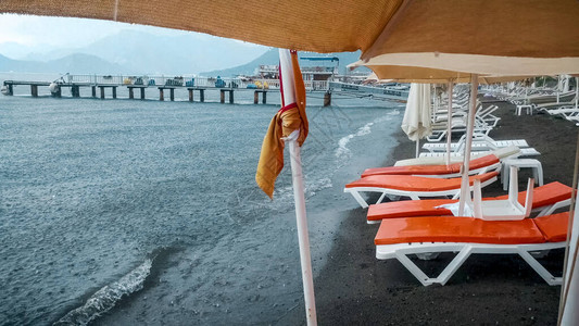 暴雨期间海滩上湿漉的日光浴床和遮阳伞图片