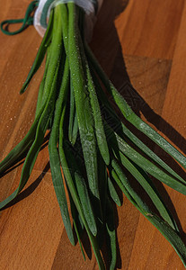 棕色木质背景上的鲜葱带水滴的大葱可重复使用的白色购物袋中的洋葱新鲜多汁的春菜健康食品饮食素食图片