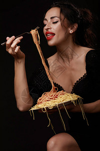 一个红嘴唇的漂亮女孩吃全盘面的叉子意大利面条图片