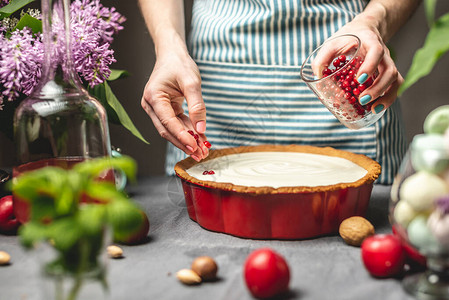 一位女糕点厨师正在用白酸奶油在林边莓酱上洒红莓果子背景图片