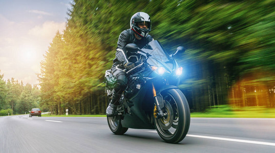骑在森林路上的汽车驾驶员在摩托车旅行中驾着空路图片