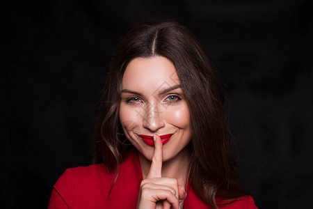 一个黑发白种女人穿着红色衣服和黑色背景上的红唇的情感头像她用手指靠近背景图片