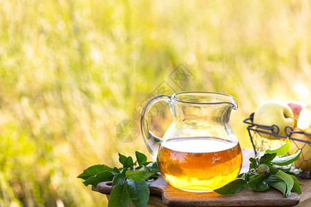 玻璃壶配苹果醋或苹果汁和木制自然背景上的新鲜成熟苹图片