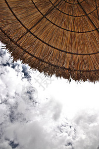 天空前稻草遮阳伞的底视图图片