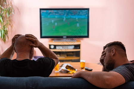 父亲和儿子在电视上看橄榄球或足球图片
