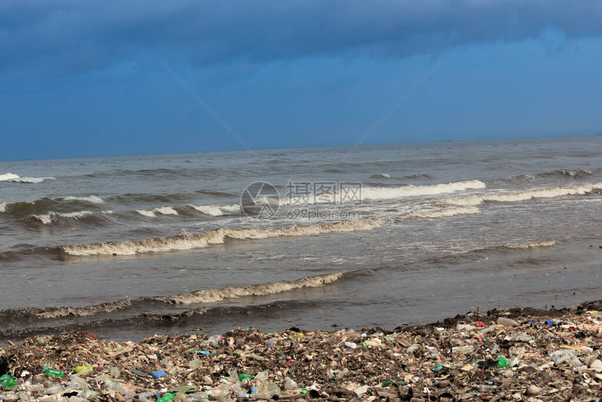 妇女从海上冲浪带来的垃圾堆里收集塑料制图片