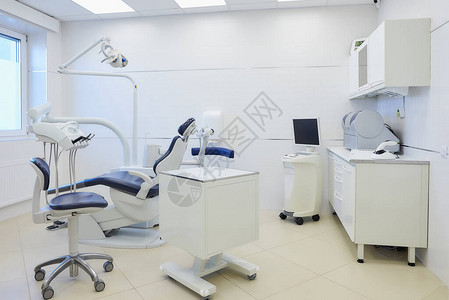 牙科诊所的内部配有白色和蓝色家具牙科椅湿磨和研磨机口内扫描仪led聚合灯牙医办公室背景图片