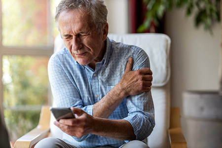 老人在家使用智能手机时经历疼背景图片
