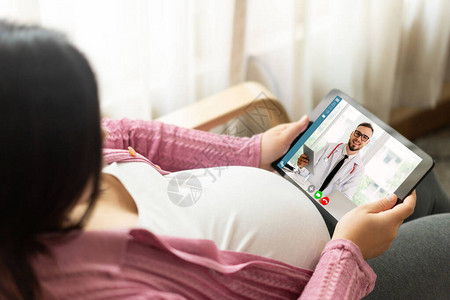 医生远程医疗服务在线视频与孕妇进行产前护理在家中使用在线移动设备连接到互联网进行实时视频通话的远程医生图片