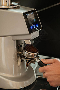咖啡师研磨咖啡的特写专业的咖啡师工作用咖啡机煮咖啡热倒饮料概图片