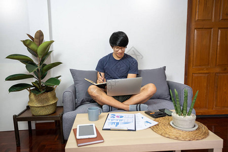 英俊的亚洲自由职业者在家远程使用笔记本电脑工作图片
