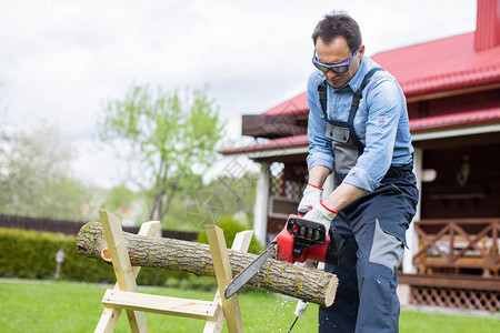男人在锯木头准备取暖电锯和伐木工借房贷在户外砍树人为炉切割木材原木工手工背景图片