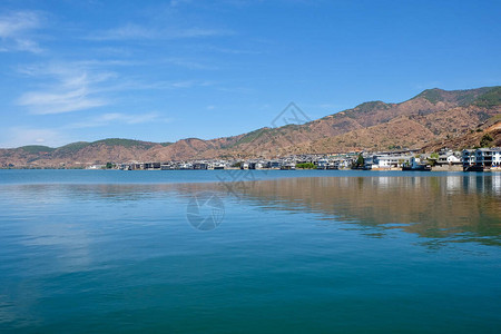云南双浪蓝色洱海沿岸的山脉和客栈在平静的水中对称反射晴朗的图片