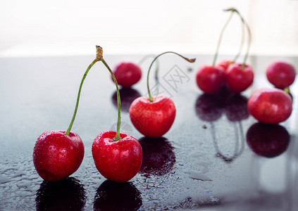 被水浸湿的红樱桃在黑色镜面背景下反射图片