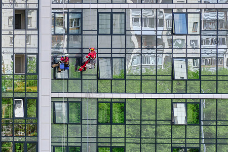 清洁服务的两名工业登山者洗刷了现代高楼公寓大楼的玻璃面孔图片