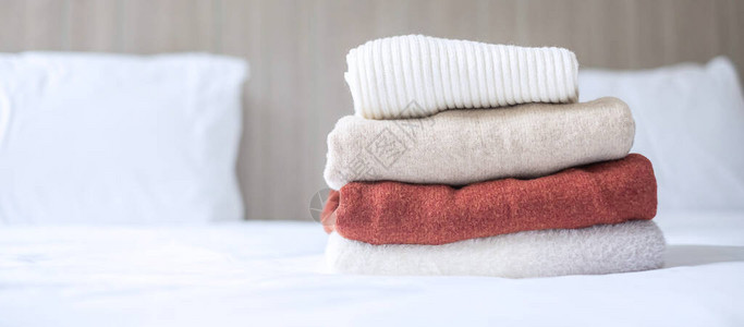 在豪华酒店度假村或家中的床上堆放米色羊毛衣放松秋装或冬装洗背景图片