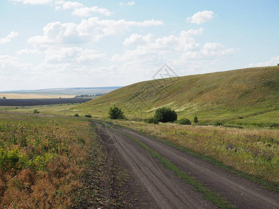 公路穿过农村牧草地小麦田和干草堆收割山丘图片