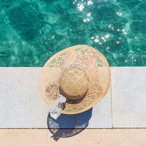 身着夏日大太阳帽的女士在码头上在清澈背景图片