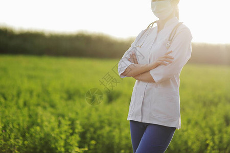 在绿草背景下戴防护面罩的女医生或护士针对冠状的安全措施预防Covid19医疗保健概念听诊器挂在脖子上图片
