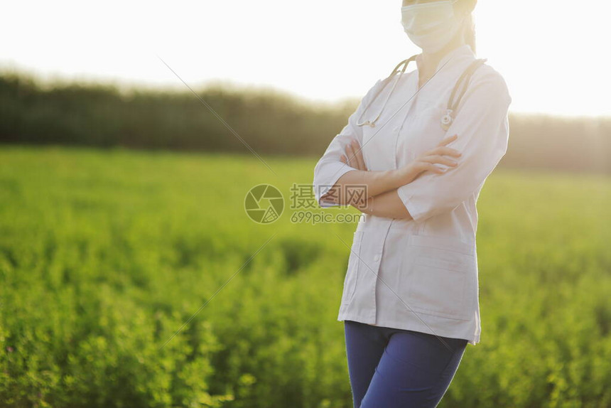 在绿草背景下戴防护面罩的女医生或护士针对冠状的安全措施预防Covid19医疗保健概念听诊器挂在脖子上图片