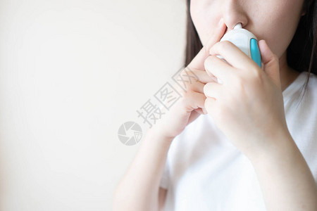 年轻女使用类固醇鼻喷雾悬浮液来缓解打喷嚏流鼻涕或鼻子发痒等症状用于治疗过敏鼻炎花粉热鼻窦炎或鼻息背景图片