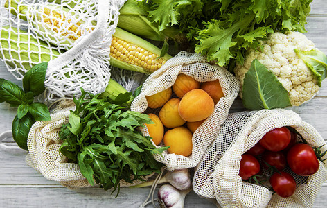 厨房桌子上的生态棉袋中的新鲜水果和蔬菜玉米杏子西红柿芝麻菜市场上的沙拉零图片