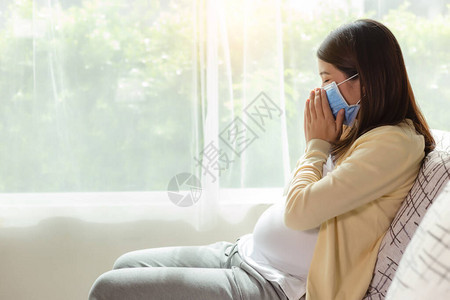 亚洲孕妇患感冒或流感和咳嗽戴面罩的年轻孕妇独自在家进行自我隔离检疫预防covid19图片