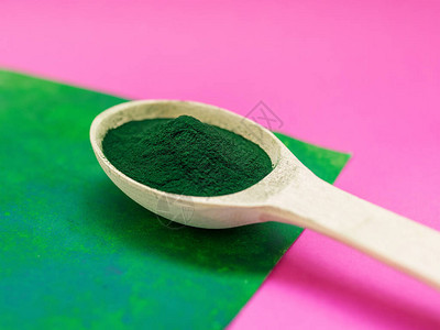 粉红色和绿色背景的木勺粉中的绿色夏威夷螺旋藻超级食物健康生活方式健图片