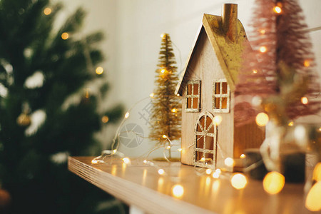 圣诞节快乐时尚的圣诞木屋闪发光的圣诞树和节日灯光下的驯鹿微型童话村图片