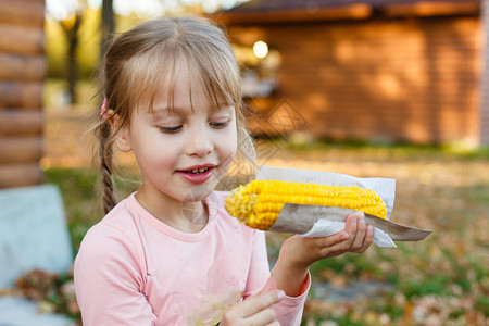 小女孩在玉米棒上吃凌乱的玉米图片
