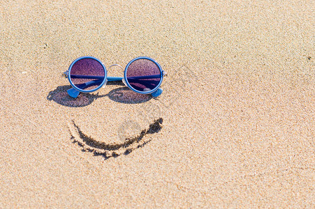 太阳镜和沙滩上的彩绘微笑旅游理念图片