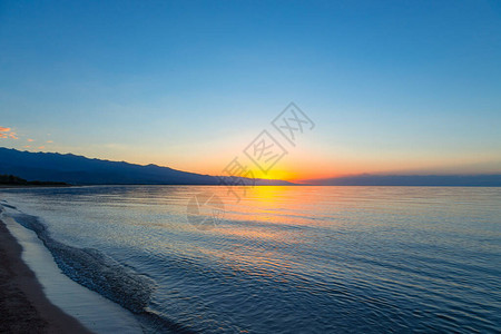 海上太阳的黎明山后初升的太阳背景图片