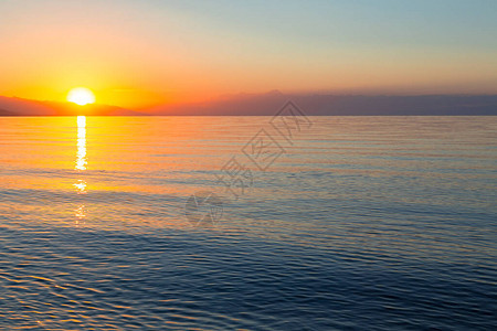 海上太阳的黎明山后初升的太阳背景图片