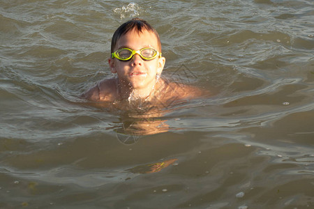 一个10岁男孩穿绿色游泳护目镜在海岸附图片